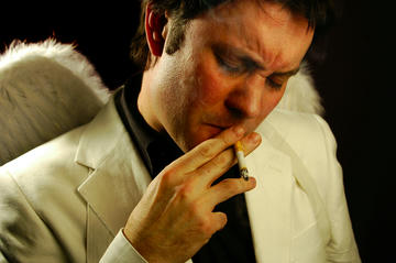 Chas Early as Bill Hicks, wearing angel wings and smoking a cigarette.
